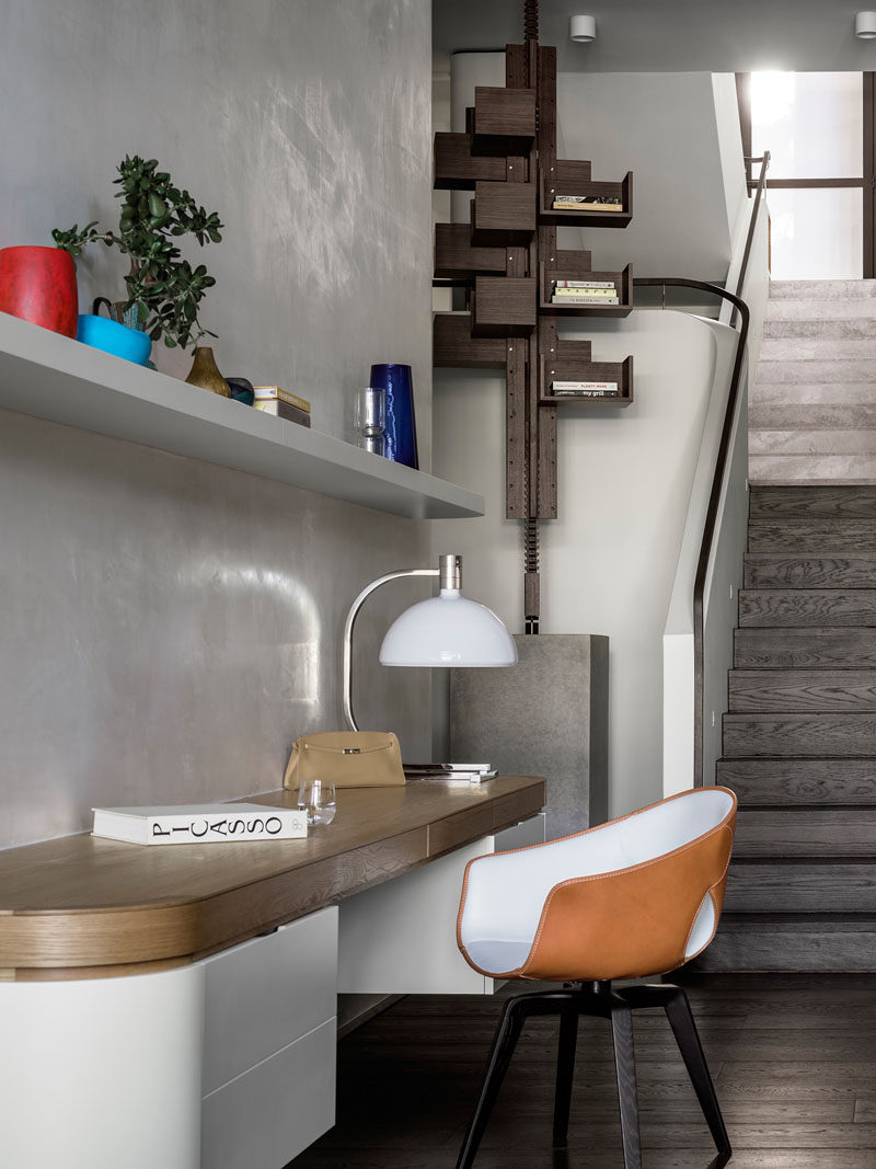 On the walls of this modern house, instead of painting over the gypsum plaster, the architects gently (and without excessive buffing) applied a clear beeswax to create a soft lustre and a smooth waxy texture. A small home office area with a white floating shelf sits against the wall.