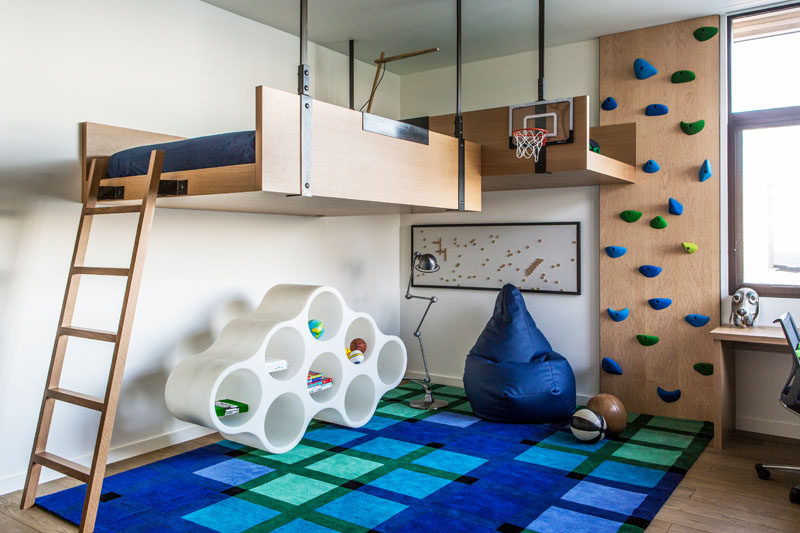 In this modern kids bedroom, there's two beds that are mounted to the wall and hang from the ceiling. To reach the beds, there's a ladder or a rock climbing wall. #KidsBedroom #LoftBed