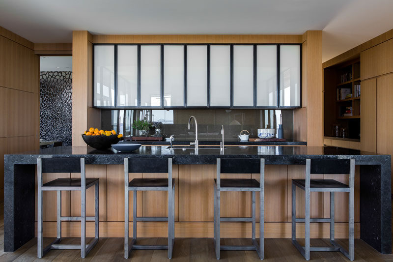 This modern kitchen has a large stone island with a wood base and plenty of room for seating. #ModernKitchen #KitchenDesign #KitchenIdeas