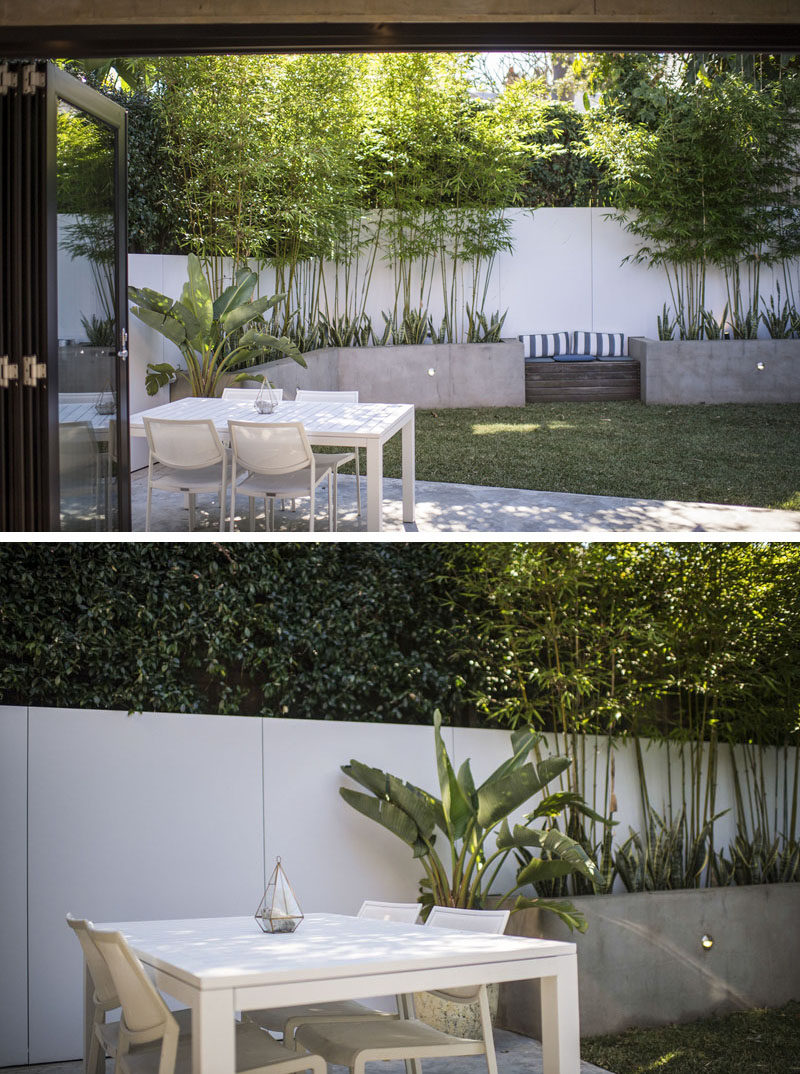 This modern landscaped backyard has custom planters that wrap around wall, a built-in wood bench and an outdoor dining area. #BuiltInPlanters #Landscaping #Backyard #ModernBackyard