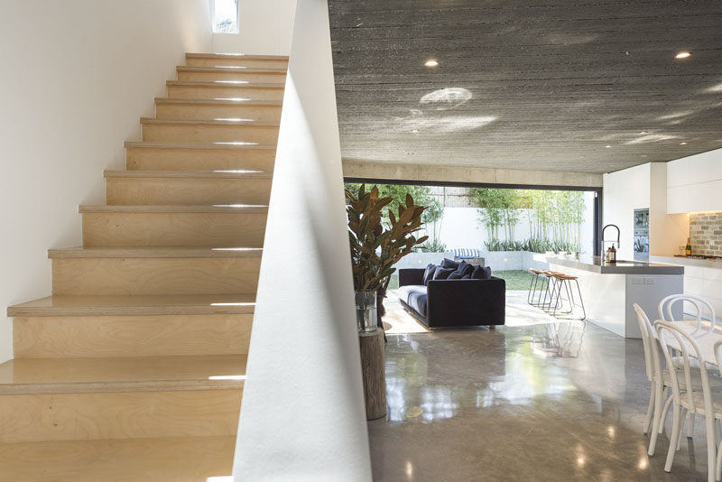 This modern house with concrete floors and ceilings features light wood stairs that lead up to the second floor of the home. #ModernHouse #LightWoodStairs #Stairs #Concrete #ConcreteFlooring #ModernInterior