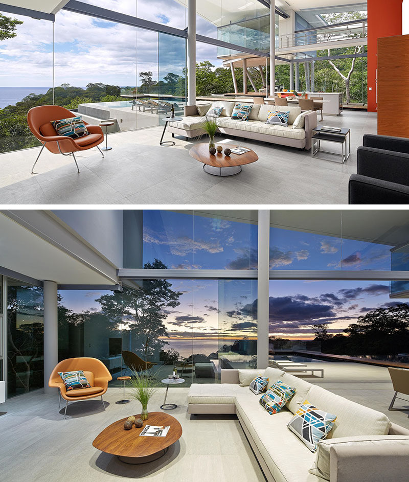 The main living space in this modern house is open plan, with the living room at one end. The floor-to-ceiling glass walls ensure that the view can always be enjoyed, and the single orange armchair ties in with the orange paint and stools used in the kitchen.