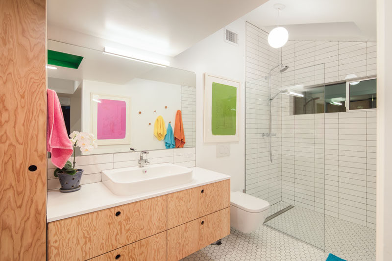 In this modern master bathroom, wood cabinets and a vanity provide storage, while while tiles have been used in the shower and a glass partition help the light travel throughout the room.