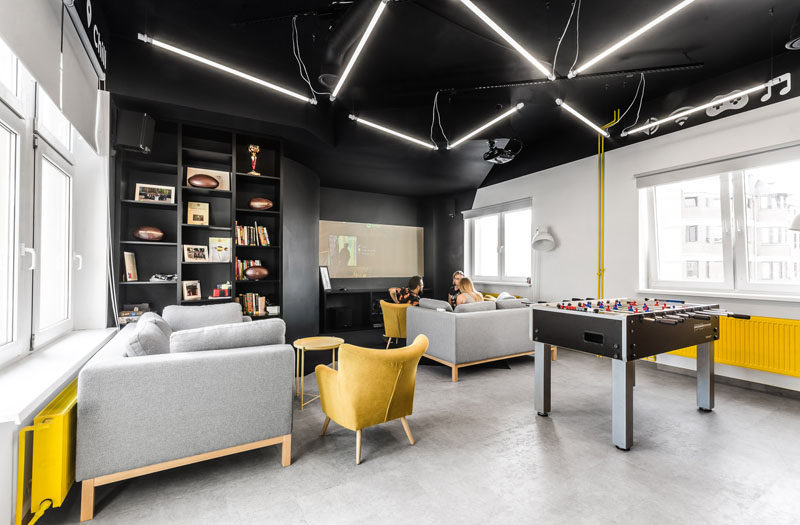 In this modern office break room, zig-zag shaped lamps hang from the ceiling, and the yellow furniture elements tie in with the lightning bolt in the company's logo.