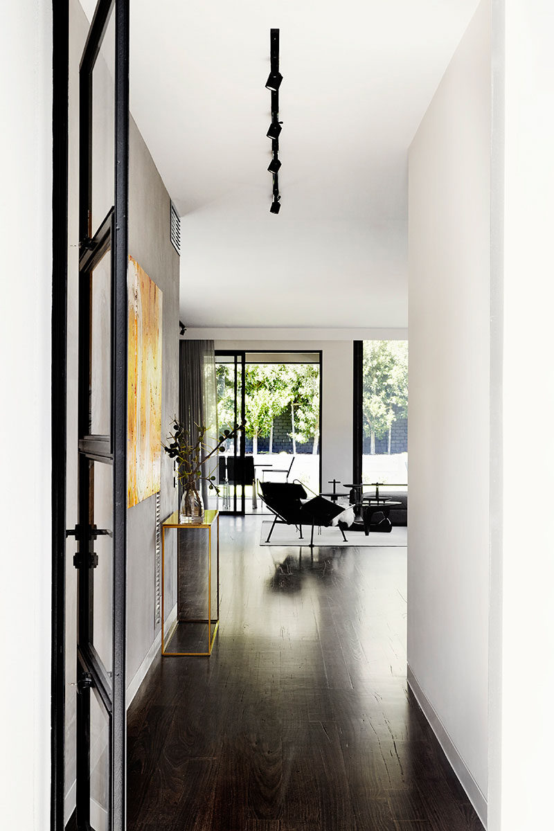 Stepping inside this modern house, white walls have been combined with dark wood floor and black elements for a contemporary and minimalist interior.