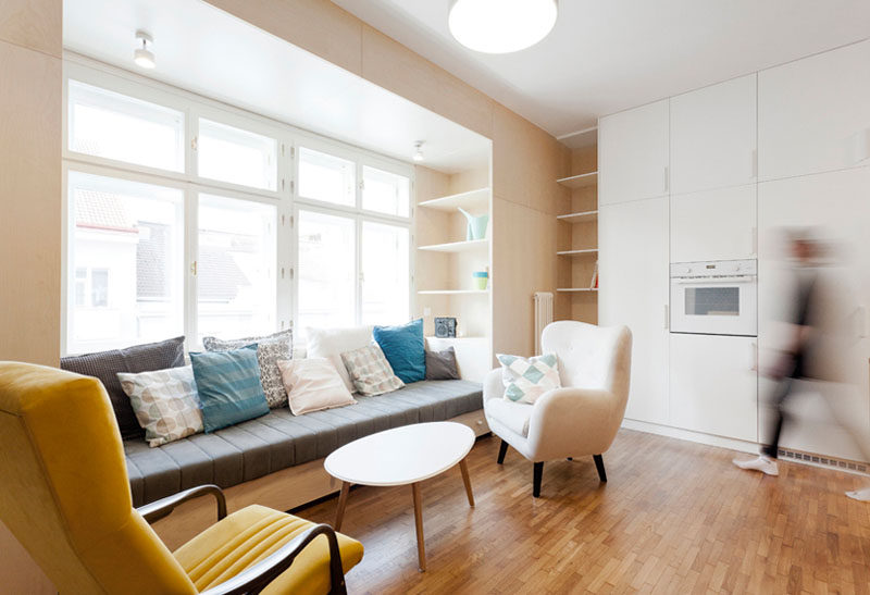 Instead of buying furniture separately and having an odd space in the living and kitchen area of this apartment, the designers created a dedicated space for lounging by using wood to create a built-in couch and shelving. #Couch #LivingRoom #InteriorDesign #BuiltInCouch #Sofa #BuiltInFurniture