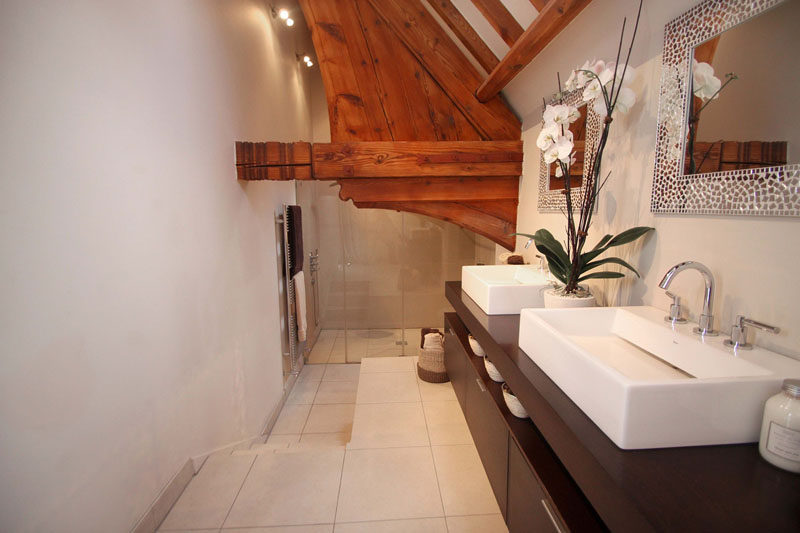 In this contemporary bathroom, the shower is stepped down from the vanity and original wood elements create a unique accent feature. #ContemporaryBathroom #WoodBeams #InteriorDesign