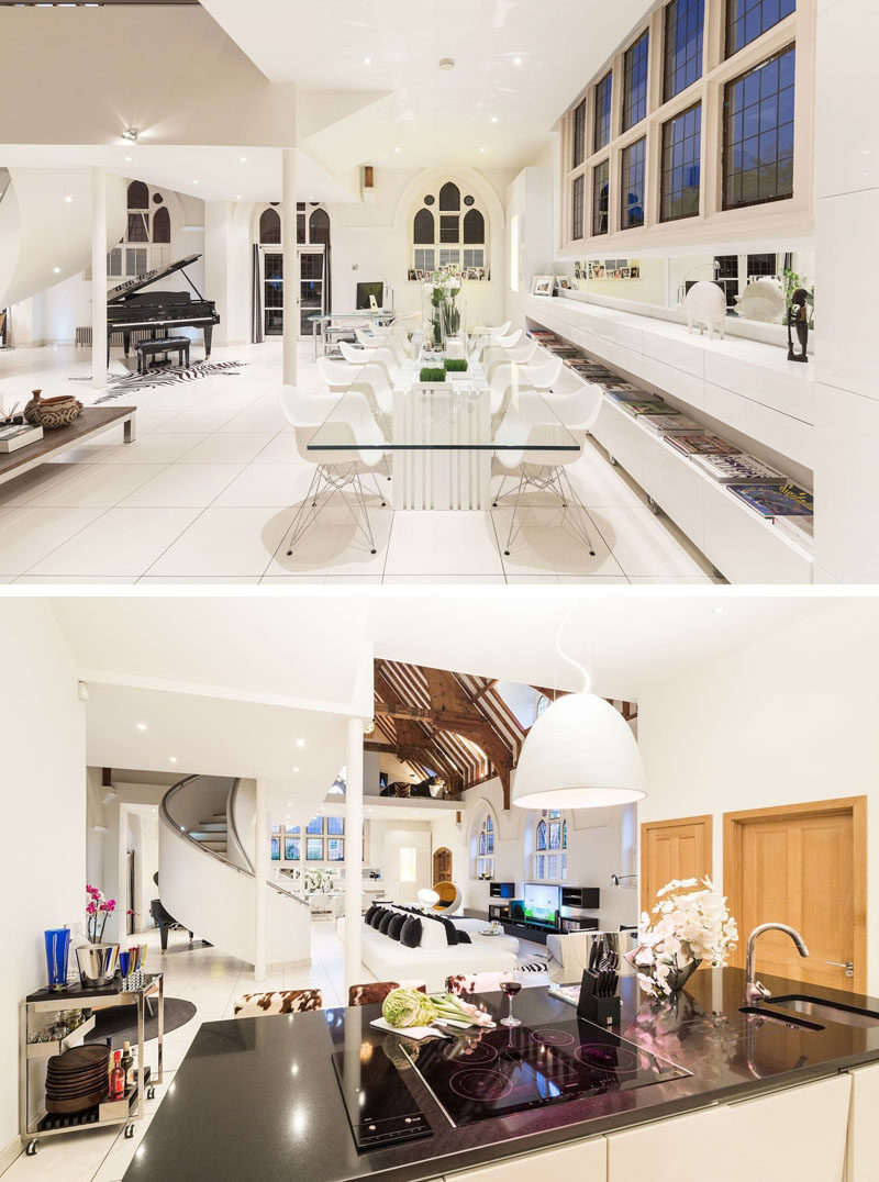 This church conversion has a modern dining room with a glass dining table with room for 12 people, and the kitchen has an island with a cooktop, sink and dark countertop. #ChurchConversion #DiningRoom #ModernKitchen #ModernInterior