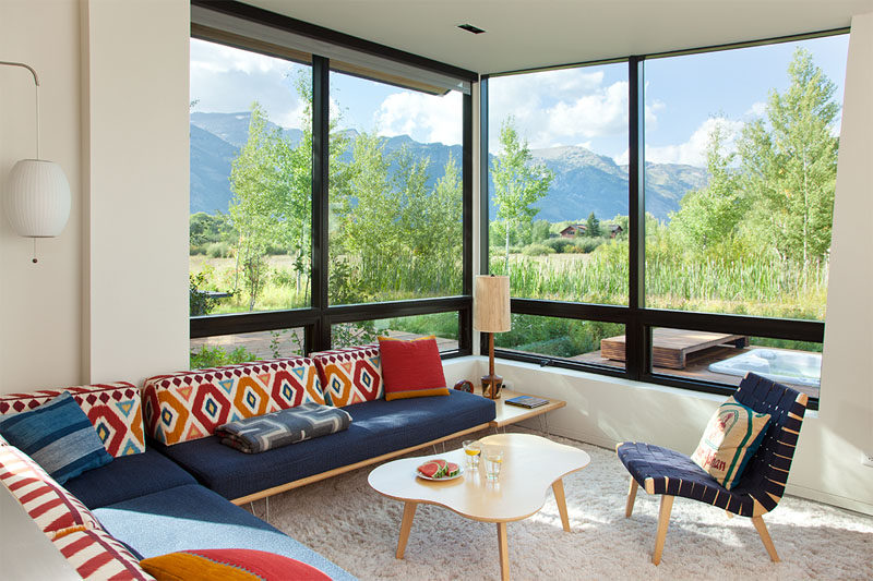 This simple and modern living room has large windows to frame the mountain views.