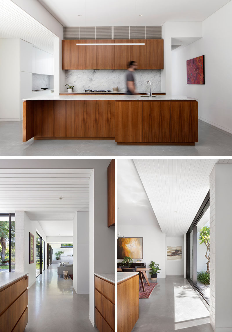 This modern kitchen features American Walnut wood cabinets, white countertops and a stone backsplash. Polished concrete floors and white walls complete the modern interior.