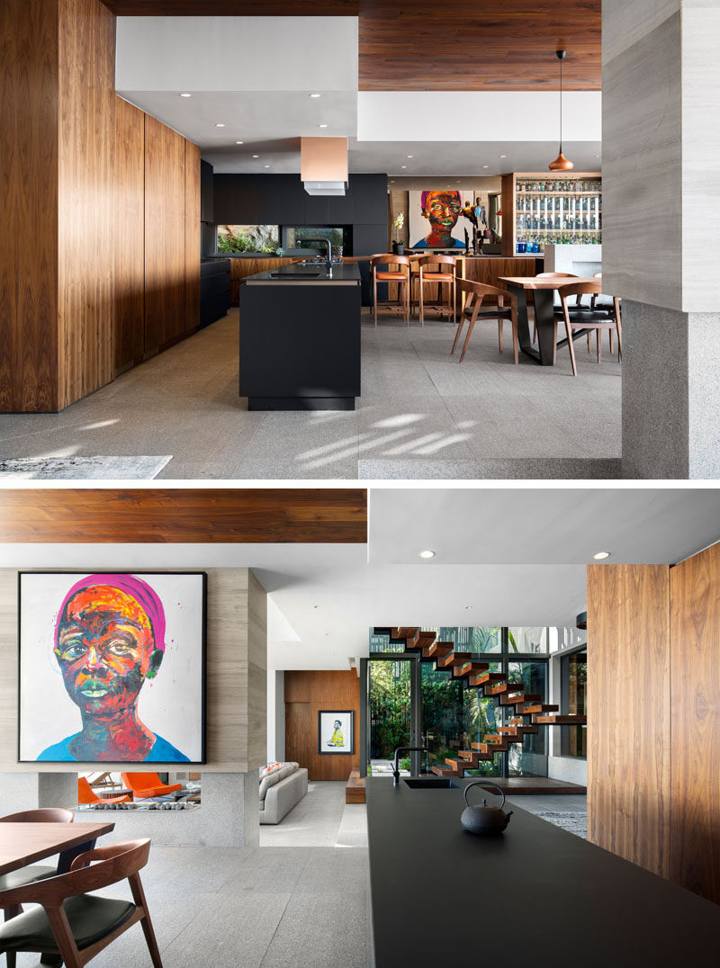 The wood and black theme of the dining area is used again in this modern kitchen, with black countertops, black and wood cabinets and a long black island.