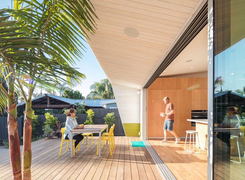 This modern house has a large sliding glass wall that opens up the kitchen and dining room to the deck and the backyard.