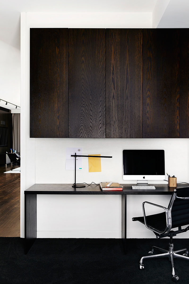 This small and modern office area has built-in dark wood cabinets and a desk large enough for two people.