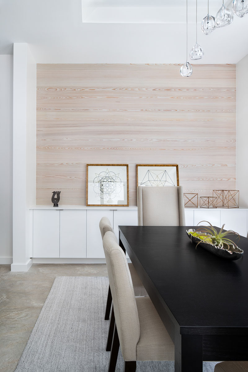 Light wood has been used as an accent wall in this contemporary dining room. Built-in white cabinets provide additional storage and acts as a space to display art and decorative items. #DiningRoom #LightWood #WoodAccentWall #InteriorDesign