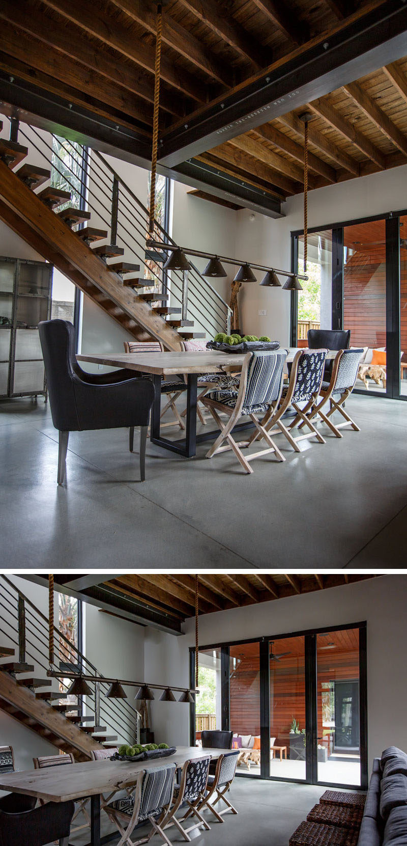 This dining area features a wood table with a steel base, and above the table, industrial inspired lighting hangs from rope attached to the ceiling. #Industrial #IndustrialInterior #DiningRoom #DiningArea