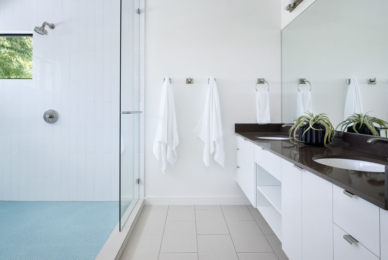 In this modern master bathroom, a large double-sink vanity with plenty of storage runs the length of the wall, while the shower is partitioned off with a glass shower screen. #MasterBathroom #ModernBathroom #BathroomDesign #Bathroom