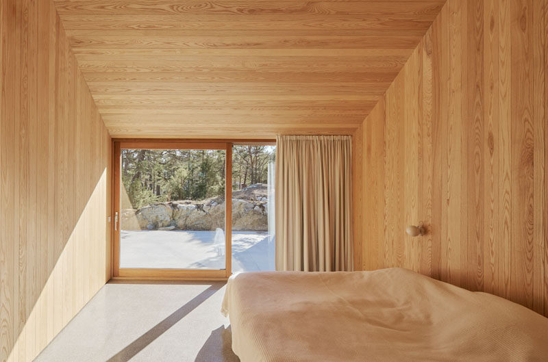 In this minimalist Scandinavian bedroom, wood lines the walls and ceiling, and a door provides access to a terrace outside. #ModernBedroom #Minimalist #Scandinavian #Wood