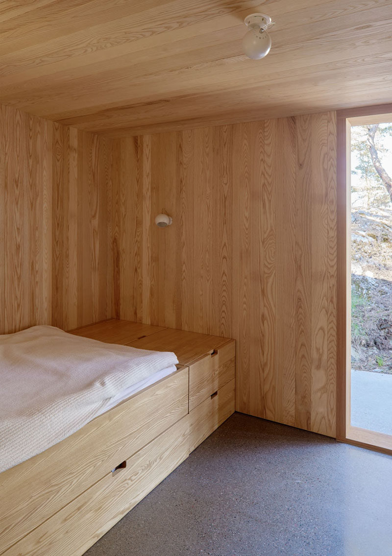 In this wood-lined Scandinavian bedroom, the bed has been raised to allow for storage or a pull-out bed, and simple globe-like lighting has been installed in the ceiling and on the wall. #ModernBedroom #Minimalist #Scandinavian #Wood