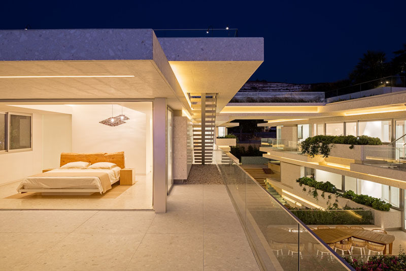 This modern master bedroom opens up to a large balcony with a glass safety rail. #BedroomDesign #ModernBedroom #Balcony