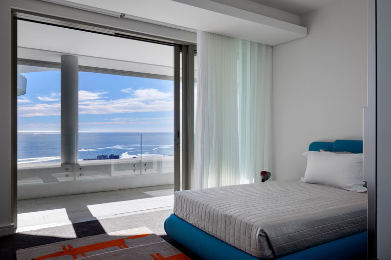 In this modern and white bedroom, a pop of color has been added with a blue bed frame and colorful rug. #ModernBedroom #WhiteBedroom