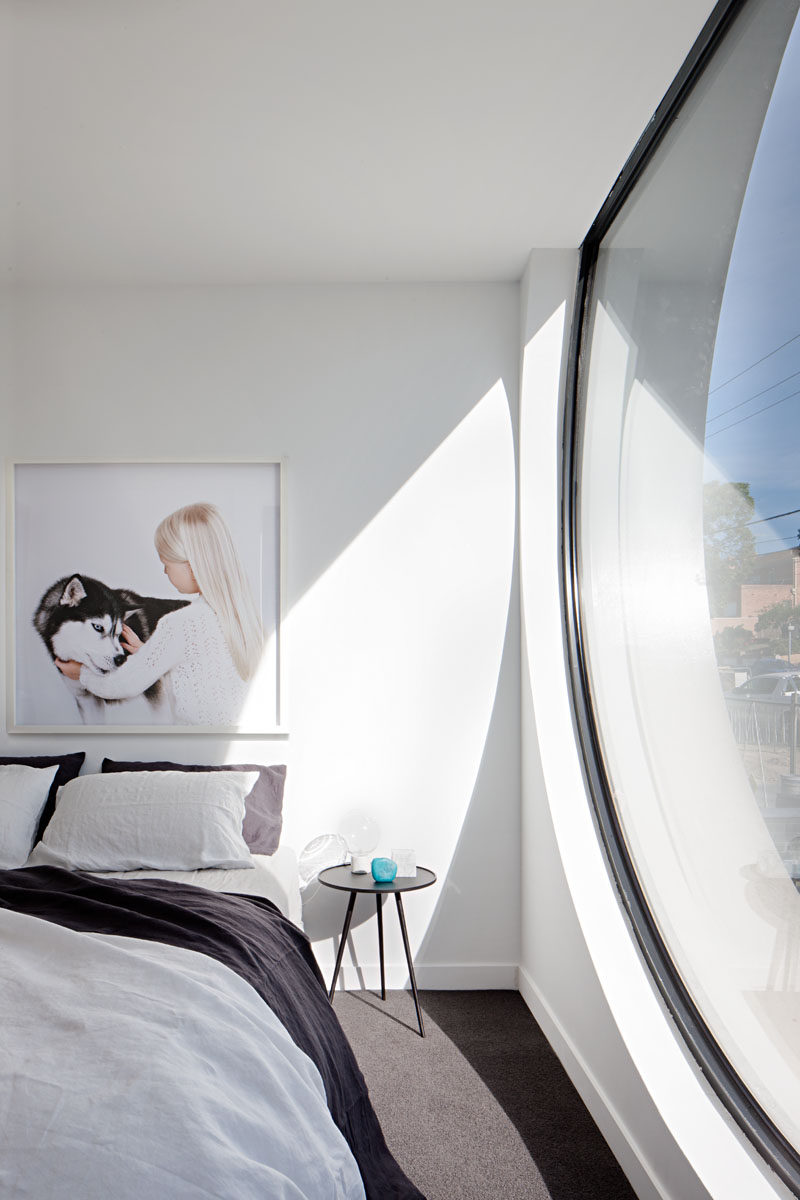 In this minimalist bedroom, a large porthole window provides plenty of natural light. #BedroomDesign #Window #InteriorDesign #ModernBedroom