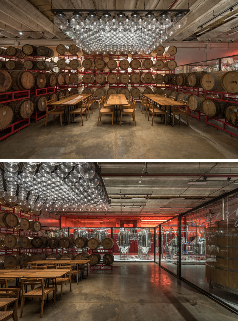 Inside this modern brewery, sets of wood tables set up for tastings are scattered among hundreds of wooden barrels that frame and divide the space. #Brewery #InteriorDesign