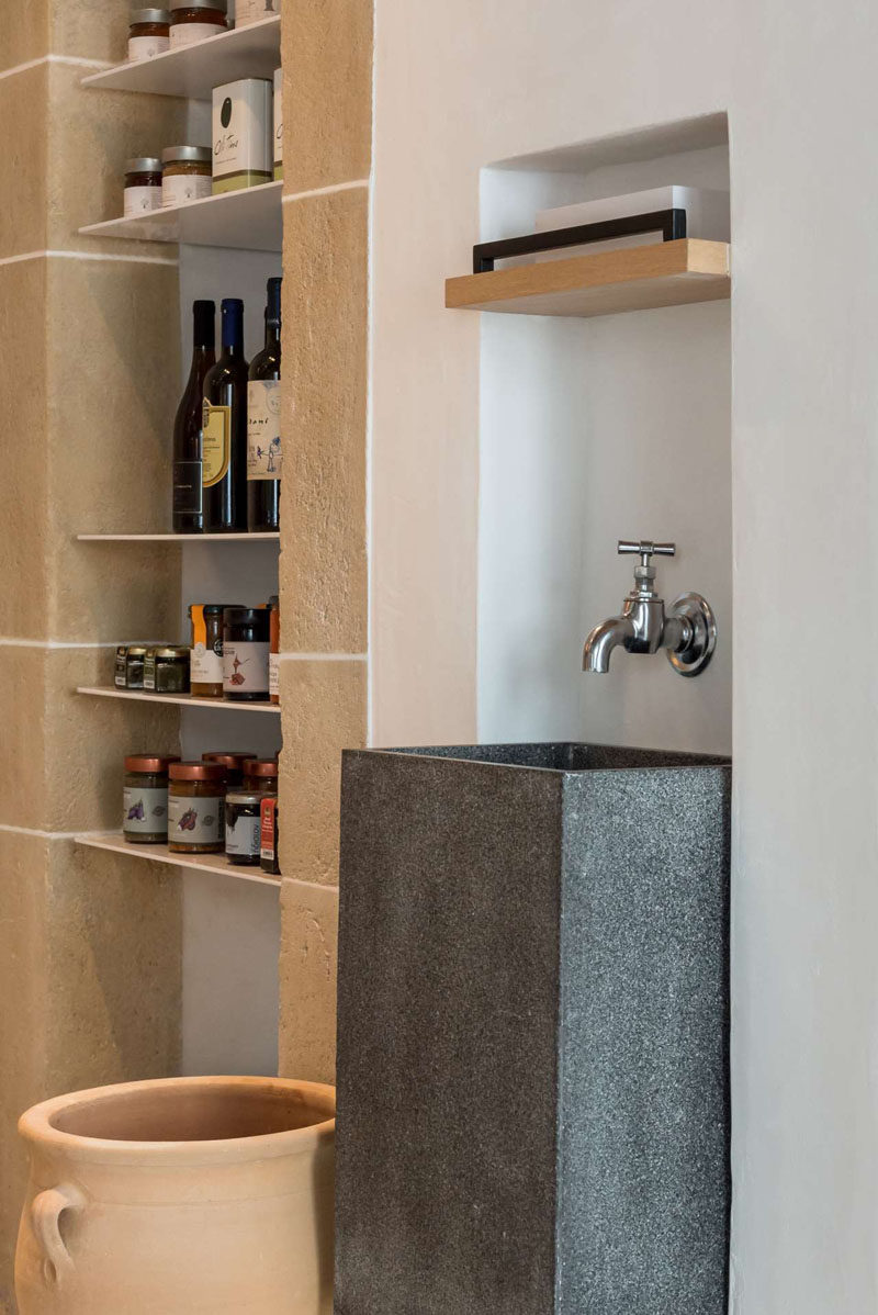 This contemporary cafe has built-in shelving with products for purchase and a tall grey sink with a single tap. #CafeDesign #CafeInterior #Cafe