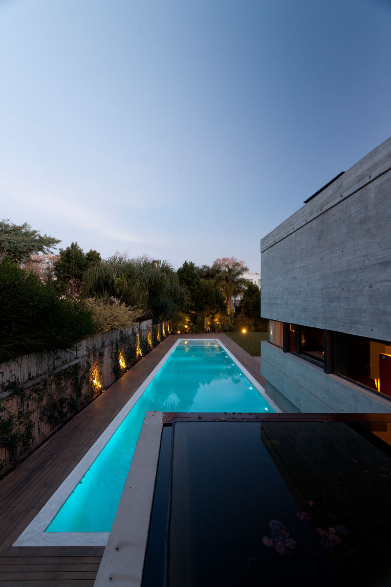 This modern concrete house has a linear swimming pool surrounded by a wood deck. #ConcreteHouse #ModernHouse #SwimmingPool