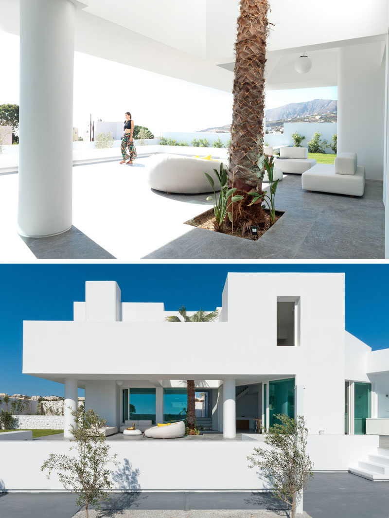 This modern house in Santorini has a partially covered outdoor lounge with a tall palm tree. #OutdoorSpace #OutdoorLounge #ModernArchitecture