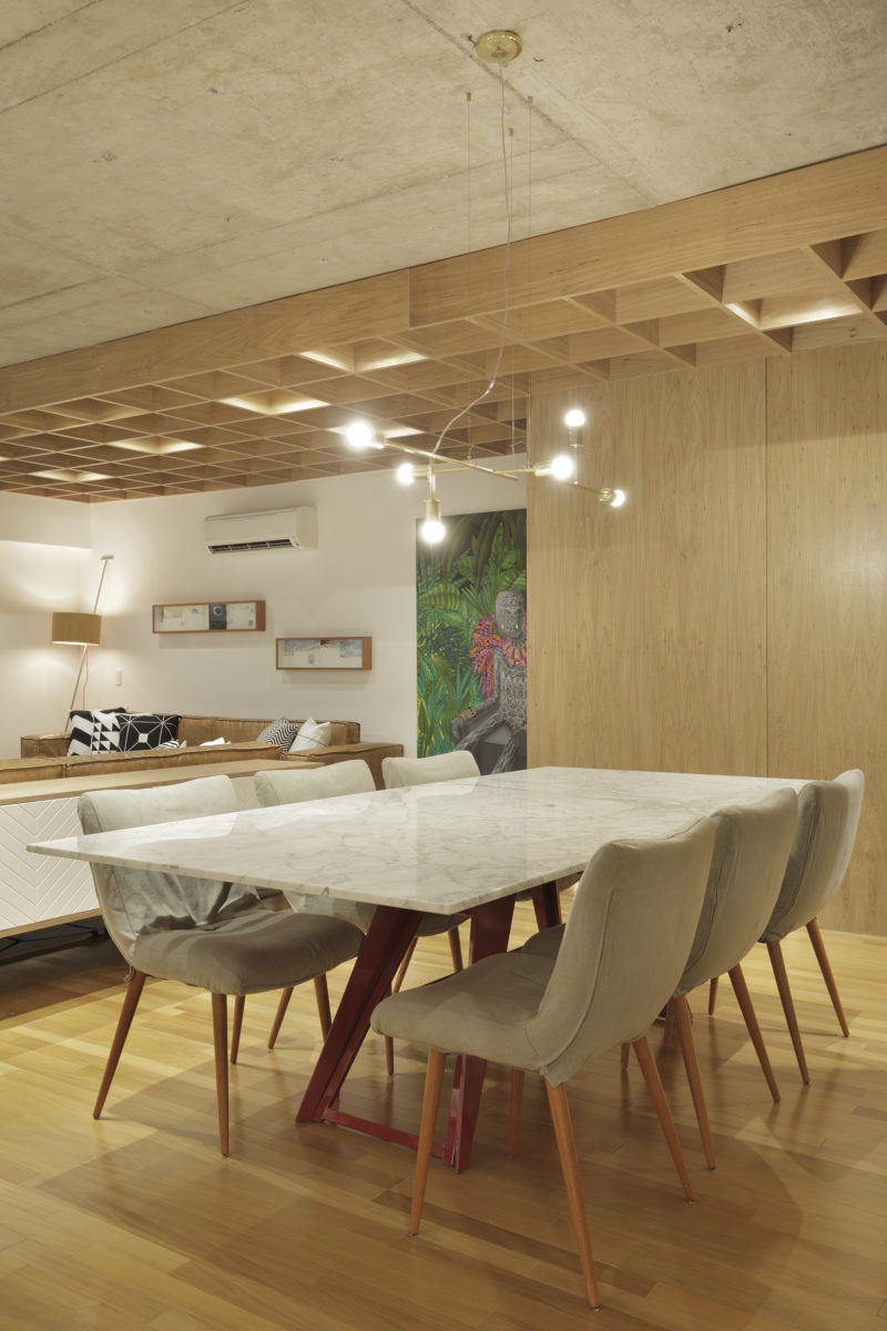 In this modern apartment, a minimalist chandelier hangs above a white dining table with natural colored chairs. #DiningRoom #ModernDiningRoom #InteriorDesign