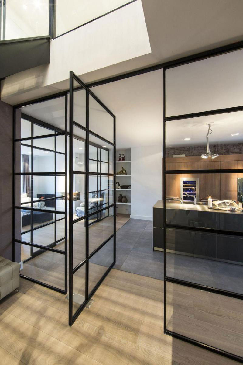 This modern apartment has a pivoting door within a black-framed glass wall. #InteriorDesign #PivotingGlassDoor #PivotingDoor #GlassWall