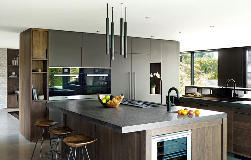 In this modern kitchen, dark wood has been paired with grey cabinets for a contemporary appearance. #GreyKitchen #Wood #KitchenDesign #ModernKitchen