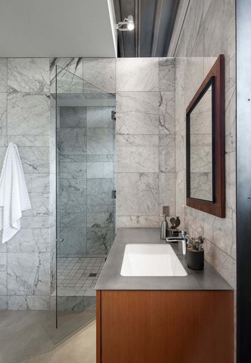 In this modern bathroom, simple grey tiles have been combined with a grey counter and wood to create a contemporary appearance. #GreyTiles #Wood #ModernBathroom