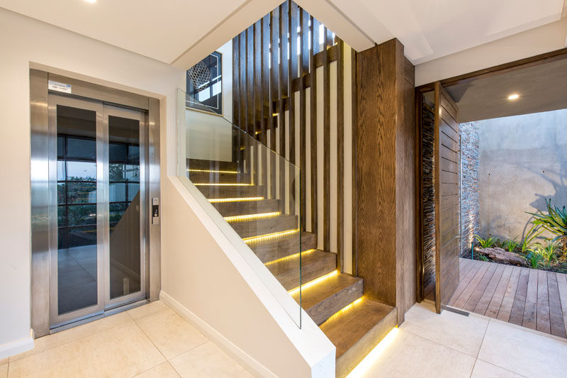 These modern wood stairs with hidden lighting and glass safety railings lead to the main floor of this house. #Stairs #HiddenLighting #ModernStairs