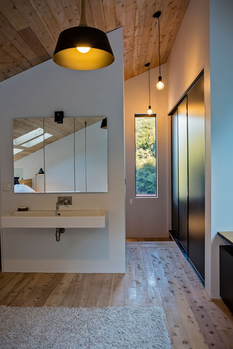 At the top of the stairs in this modern house is a built-in closet and a small vanity area. #ModernInteriorDesign #WoodCeiling #SlopedCeiling