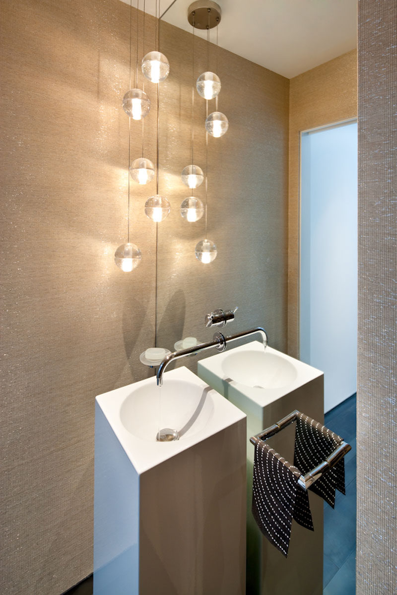 In this modern powder room, an entire wall is filled with a mirror to make the small space feel larger. #PowderRoom #LargeMirror #InteriorDesign