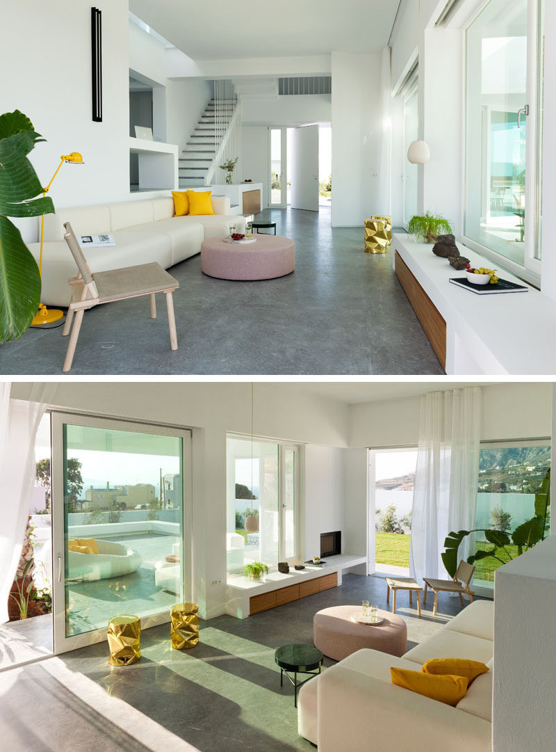 Stepping inside this modern house, the interior with white plaster walls is just as bright as the exterior. The living room has pops of color and touches of wood, while grey cement plaster has been used for the floor. #WhiteInterior #ConcreteFloors #ModernInterior