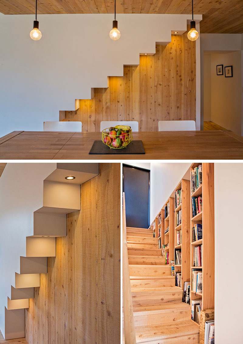 Beside the dining table in this modern house is an outline of the stairs that feature hidden lighting that highlights the design of the stairs. Wood bookshelves run alongside the stairs that lead up to the mezzanine. #Stairs #Lighting #InteriorDesign #Bookshelves #WoodInterior