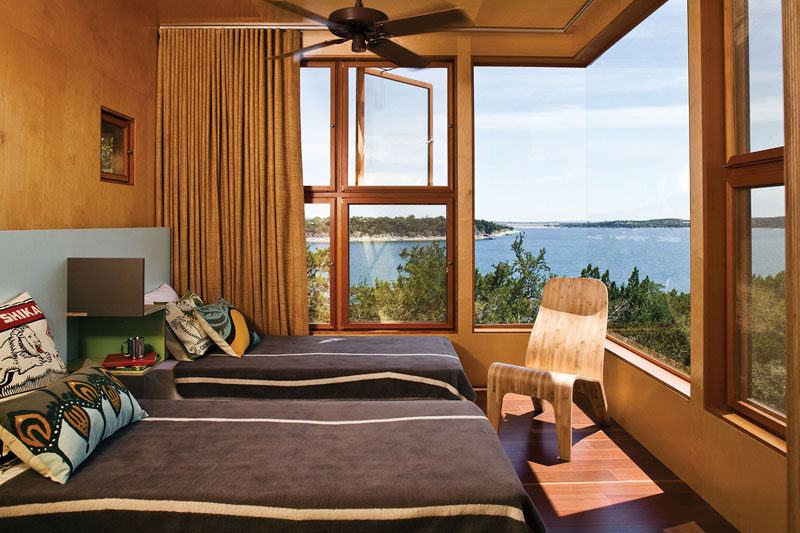 This modern bedroom has Birch plywood walls, while a large corner window reveals wide views of the woods and the lake. #CornerWindow #BirchWalls #PlywoodWalls #ModernBedroom #BedroomDesign