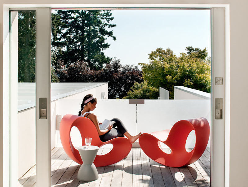 On the upper floor of this modern house there's a small outdoor space with curvaceous red chairs. #OutdoorSpace #Balcony