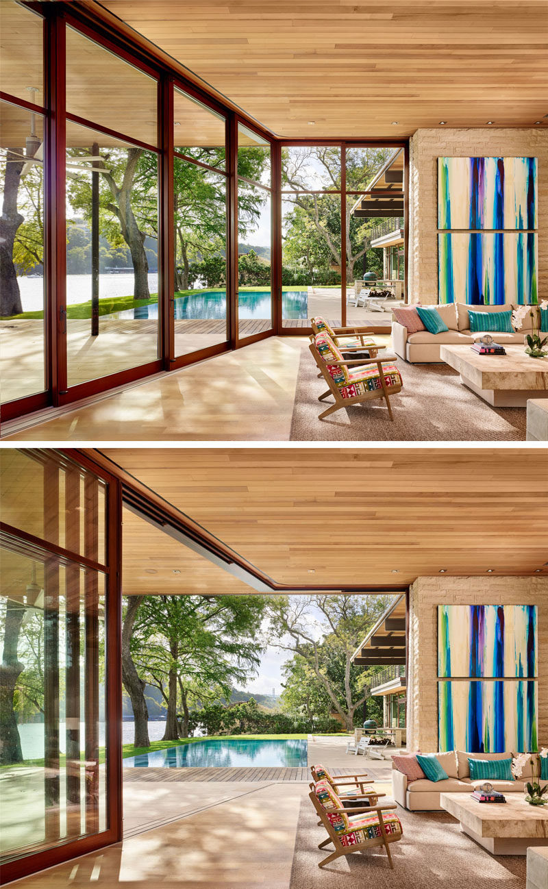 This modern and casual living room has a bright pop of color in the form of artwork and large wood-framed sliding glass walls can be opened to connect the interior living spaces with the swimming pool and deck outside. #LivingRoom #GlassWalls #Windows #IndoorOutdoorLiving #InteriorDesign