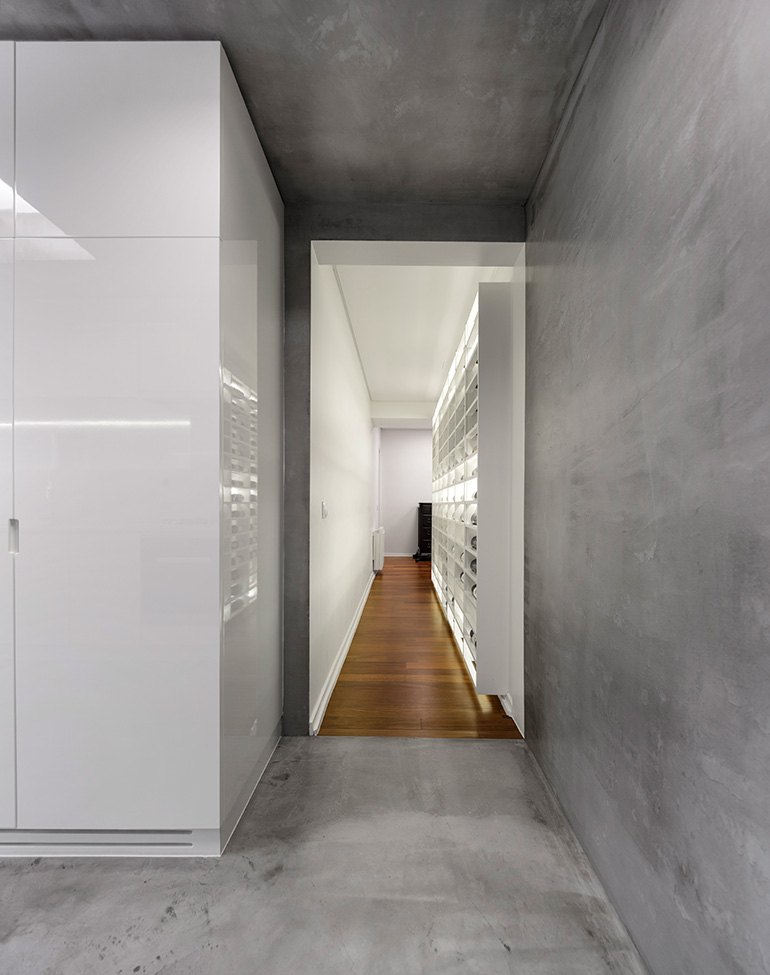 This modern apartment has a backlit wine wall in a hallway that connects the entrance hall to the kitchen. #WineStorage #WineWall
