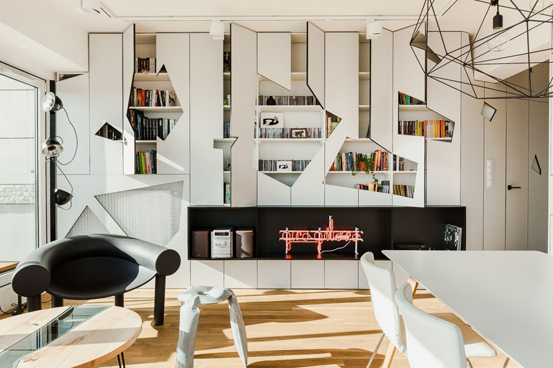 This modern apartment has a wall of white cabinets that have geometric cut-outs in the doors to add an artistic feature to the interior. #Cabinets #Geometric #LivingRoom #InteriorDesign #ModernLivingRoom