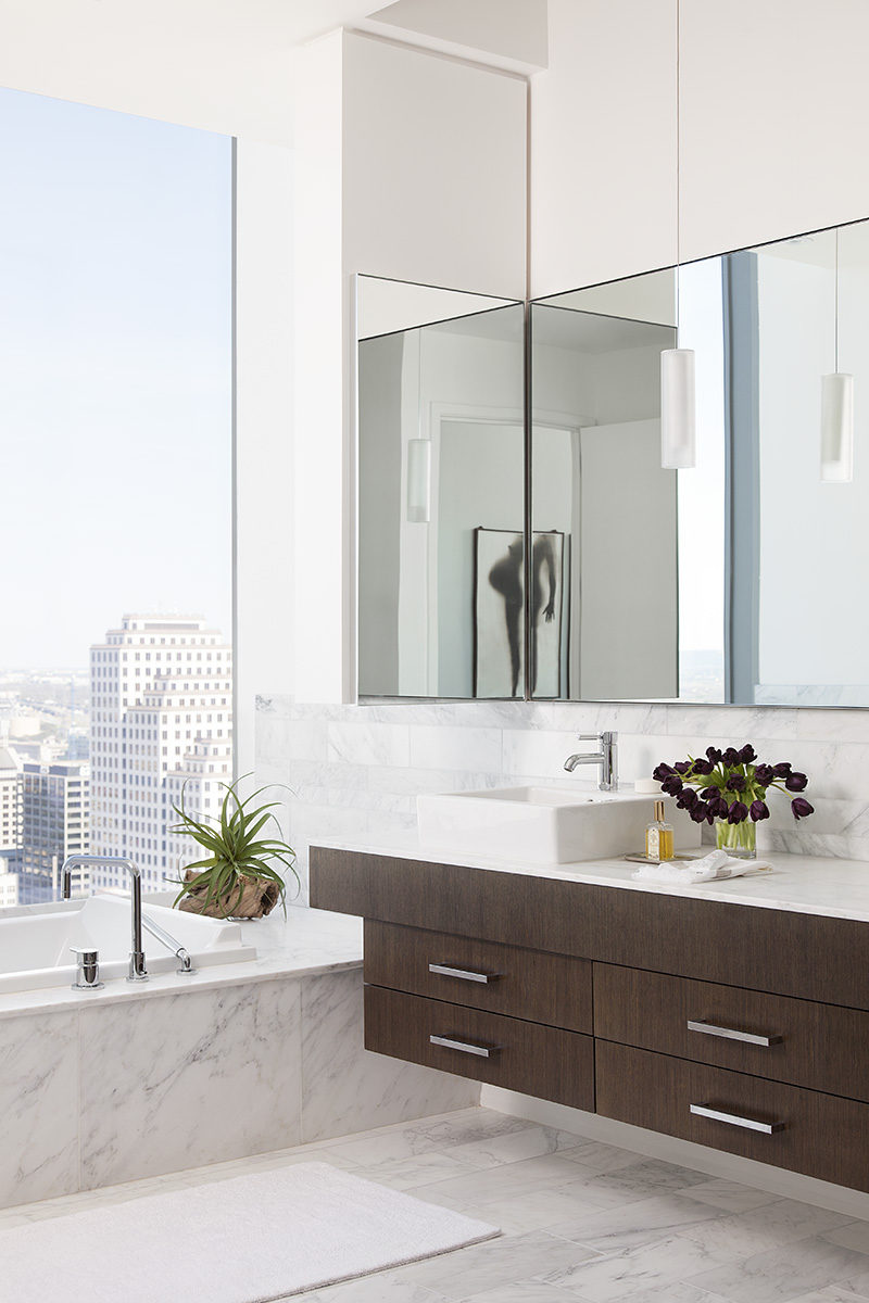 In this modern bathroom, high ceilings make the room feel larger than it is, and the bathtub has been positioned in front of the windows to take advantage of the views. #BathroomDesign #ModernBathroom #InteriorDesign