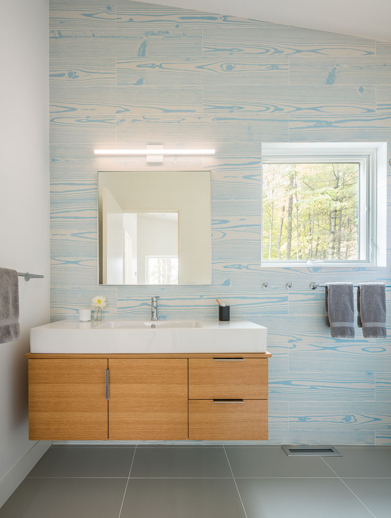 In this modern bathroom, wood grain tiles in a light blue create a unique and colorful accent wall. #ModernBathroom #AccentWall