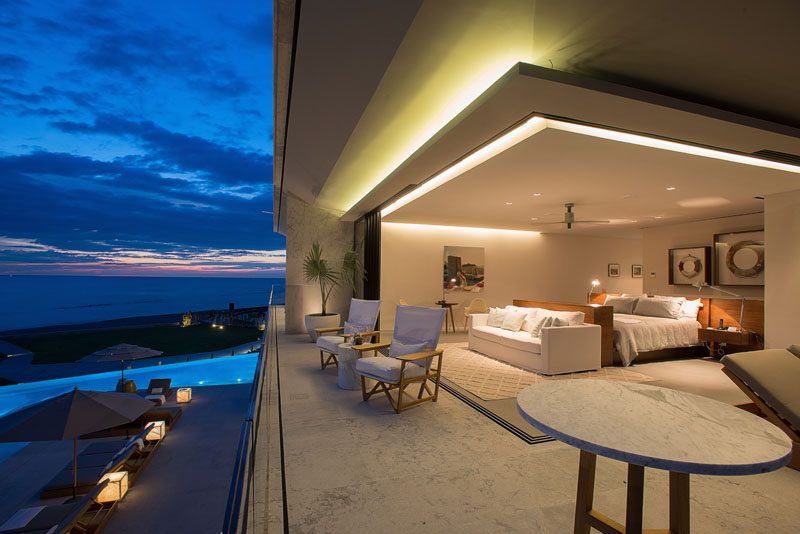 Sliding glass walls open up this modern bedroom to the balcony, and lighting is used to highlight the design elements of the home. #ModernBedroom #Architecture #Lighting