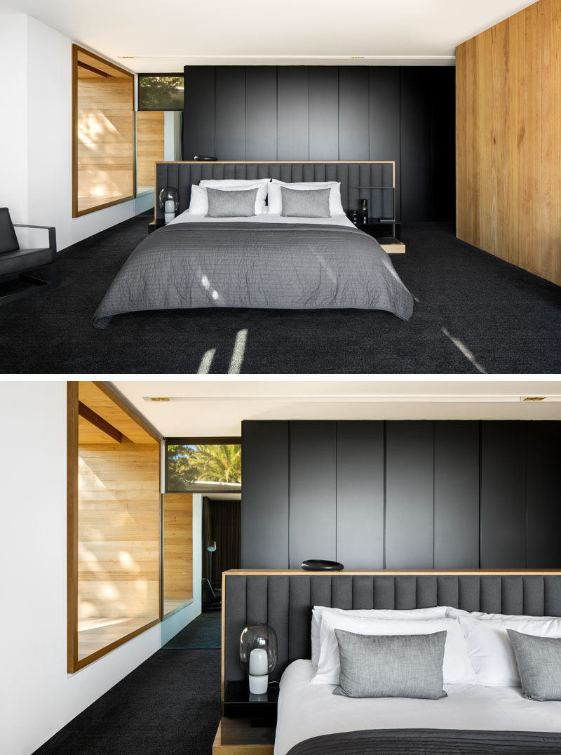 In this modern master bedroom, a window seat nook has been created and matches the wood accent wall, while black cabinetry and carpets compliments the grey tones in the bedding and on the headboard. #ModernBedroom #BlackBedroom #BlackAndWood #BedroomDesign