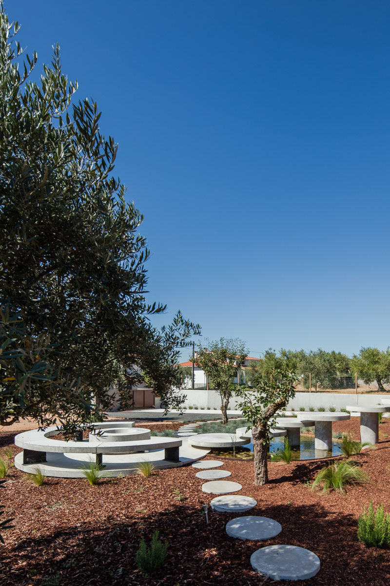 This front garden has been set up with a circular seating area with benches, a round firepit and water feature. #Landscaping #LandscapeDesign #ModernGarden #Firepit