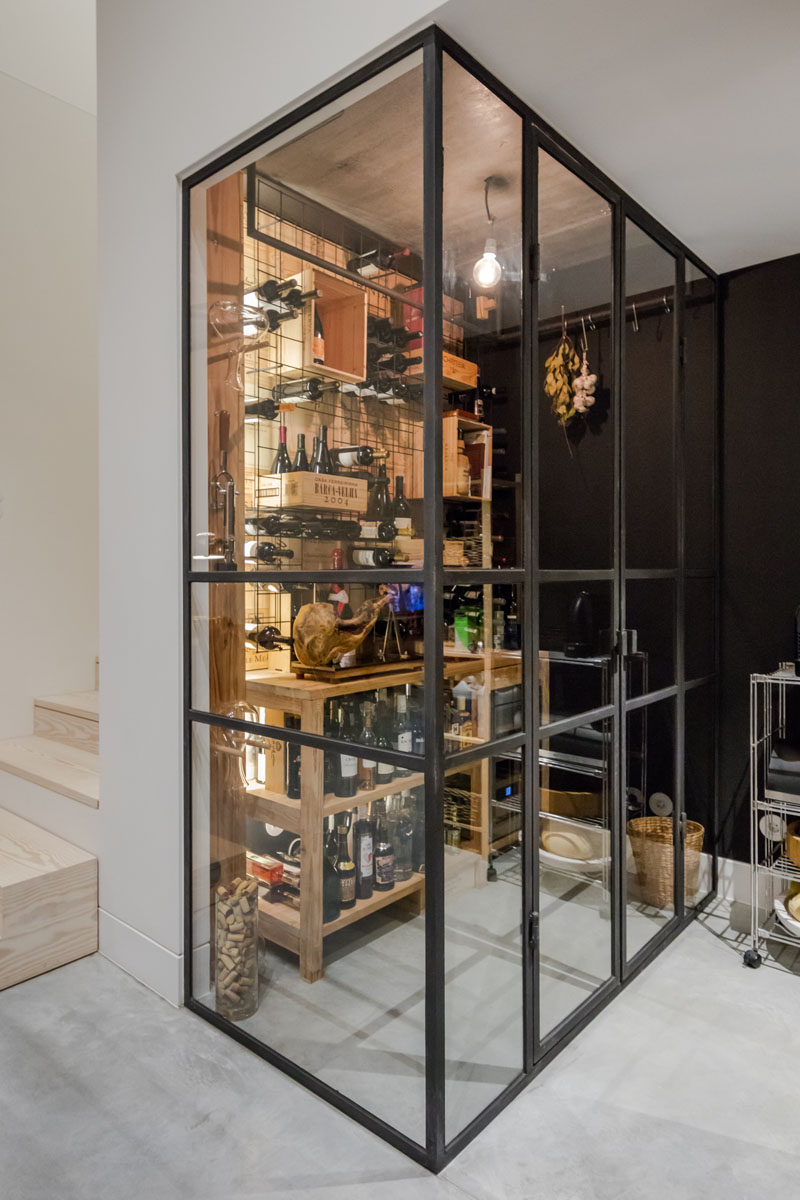 This black framed glass enclosed wine cellar has shelving and crates for wine storage. #WineCellar #WineStorage #WineRoom