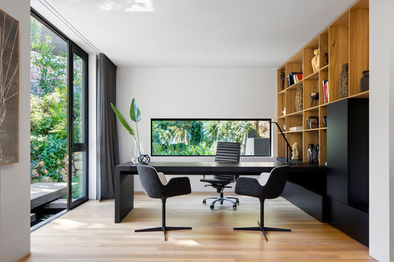 In this modern home office, built-in wood shelving lines the wall and the black cabinets match the black desk. #HomeOffice #ModernHomeOffice #WoodShelving